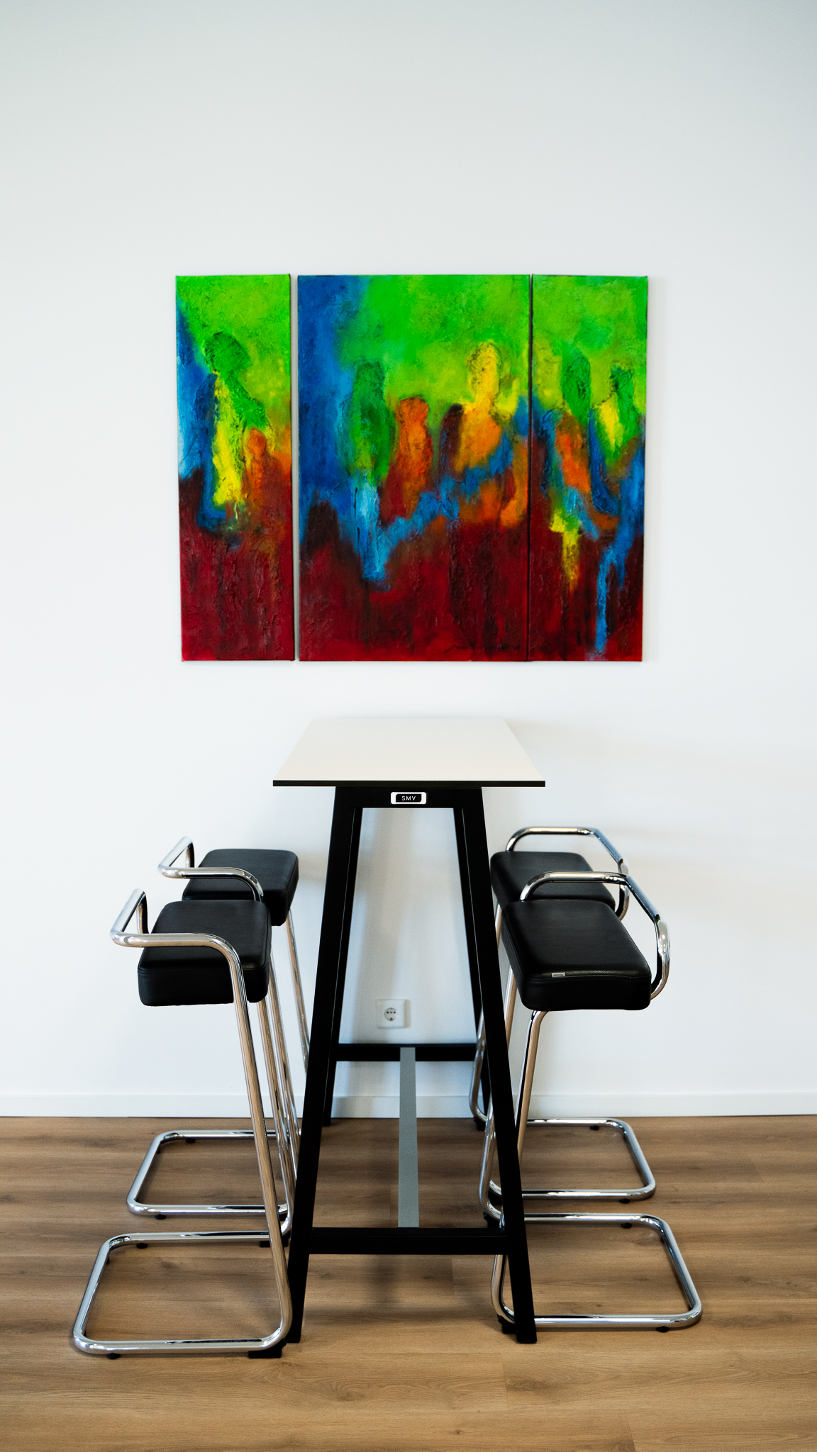 Moderne Kueche der Kanzlei, mit einem Hochtisch und Barhockern.