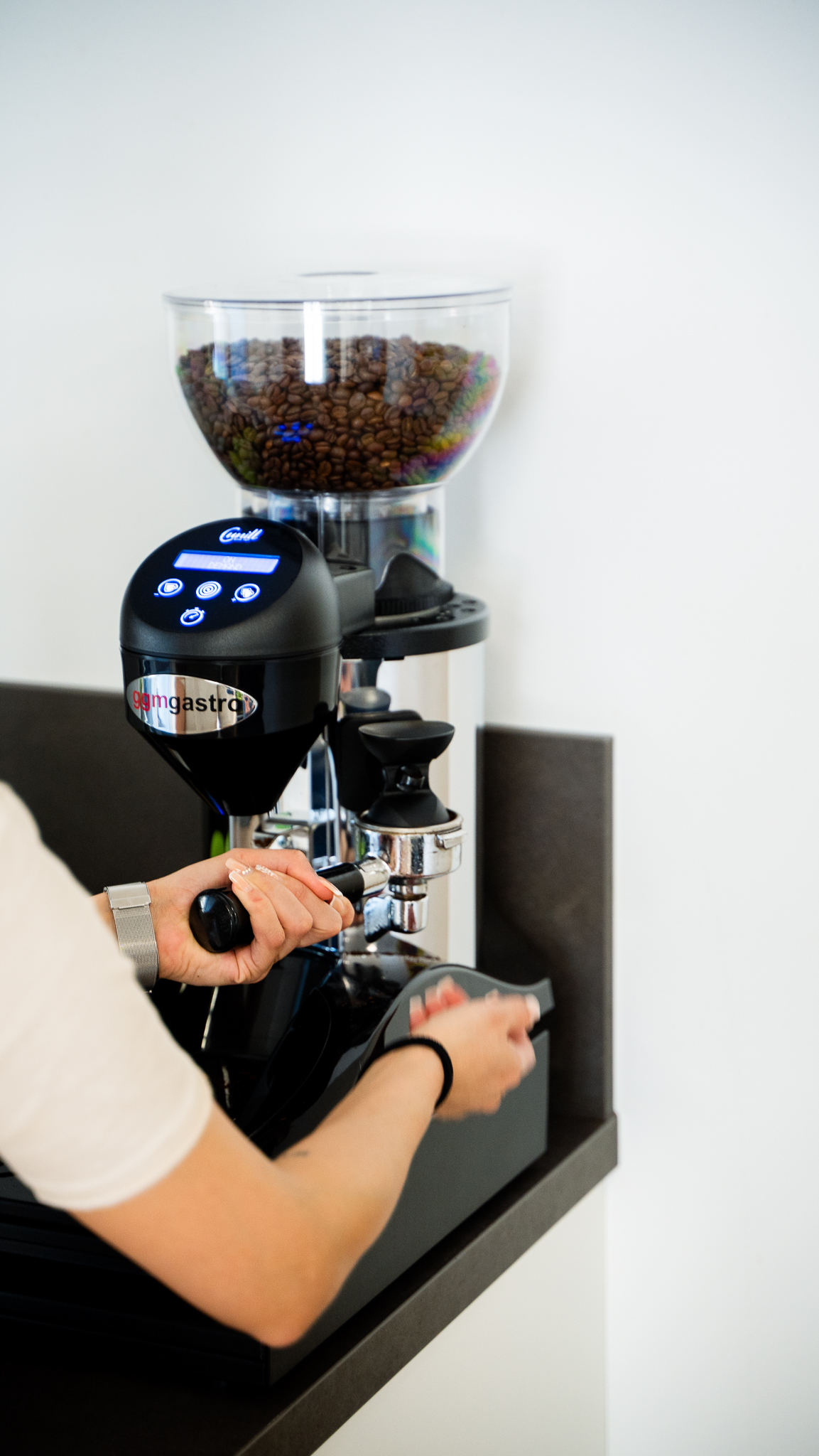 Moderne Kaffeemaschine wird von einer Mitarbeiterin betaetigt.